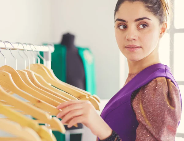 Mooie jonge stylist bij rek met hangers — Stockfoto