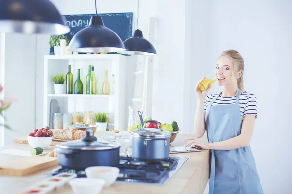 Wanita yang menarik memegang segelas jus jeruk saat berdiri di dapur — Stok Foto