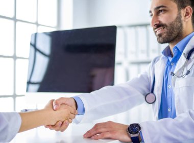 Doktor masadaki hastaya el sıkışıyor.