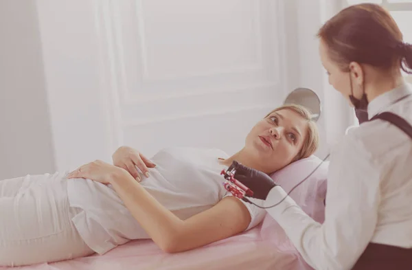 Young woman undergoing procedure of eyebrow permanent makeup in beauty salon — Stock Photo, Image