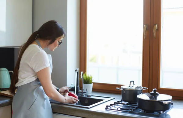 Sebze yıkayan kadın. Güzel genç bir kadın salata için sebze yıkıyor ve mutfakta dururken gülümsüyor. — Stok fotoğraf