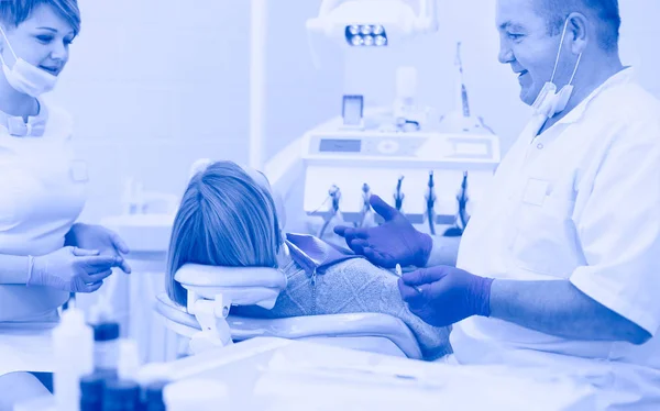 Starszy dentysta w gabinecie stomatologicznym rozmawia z pacjentką i przygotowuje się do leczenia — Zdjęcie stockowe