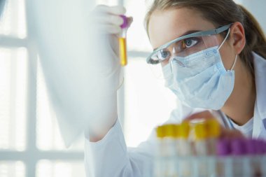 Hastanedeki kan örneğini analiz eden güzel bir kadın laboratuvar asistanı portresi.