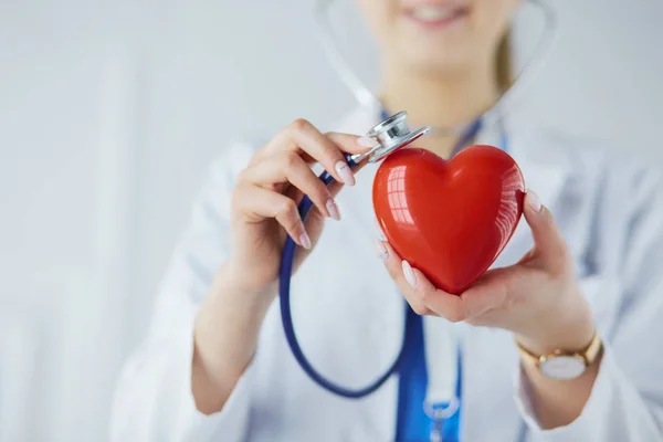 Um médico com estetoscópio examinando coração vermelho, isolado em fundo branco — Fotografia de Stock