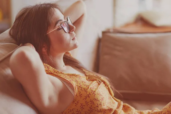 Relaxed woman sitting on a modern sofa at home