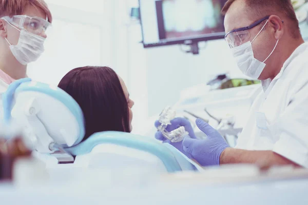 Dentistas do sexo masculino examinando e trabalhando em jovem paciente do sexo feminino — Fotografia de Stock
