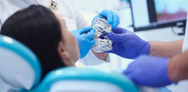 Dentista masculino senior en consultorio dental hablando con paciente femenino y preparándose para el tratamiento — Foto de Stock