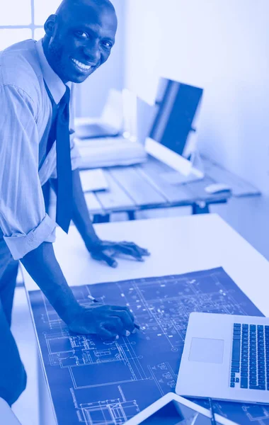 Afrikanischer Architekt arbeitet mit Computer und Bauplänen im Büro — Stockfoto