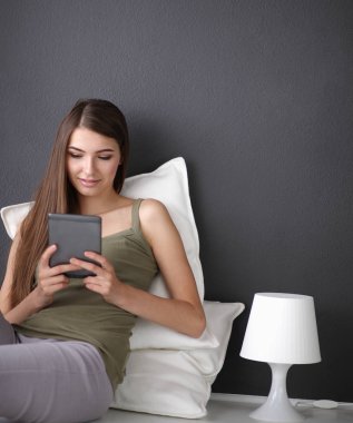 Dijital tablet kullanan kadın yerde oturuyor.