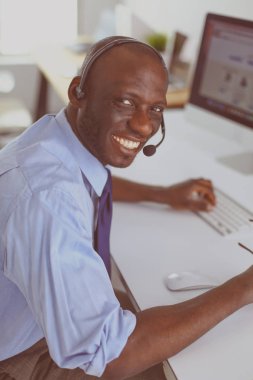 Kulaklıklı Afro-Amerikan işadamı laptopuyla çalışıyor.