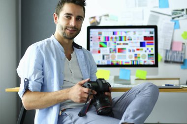 İnternette çalışırken bilgisayarın ve dizüstü bilgisayarın önünde grafik stüdyosunda oturan genç tasarımcının portresi.