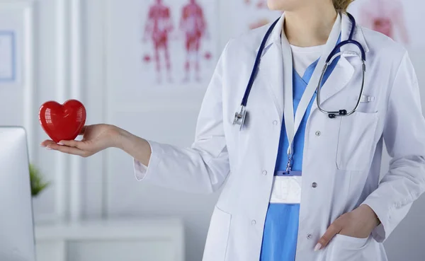 Женщина-врач со стетоскопом, держащая сердце на светлом фоне — стоковое фото