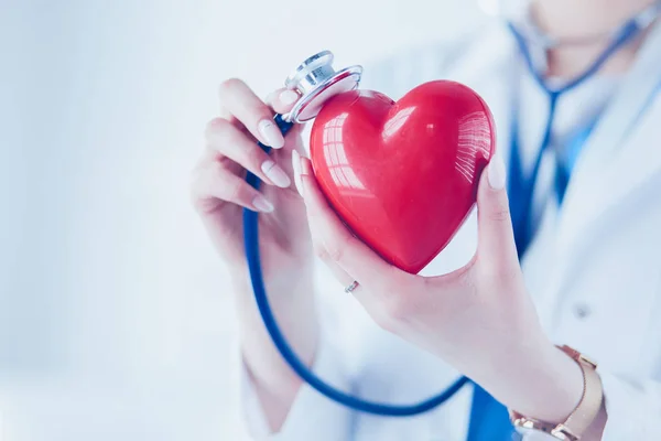 Ein Arzt mit Stethoskop untersucht rotes Herz, isoliert auf weißem Hintergrund — Stockfoto