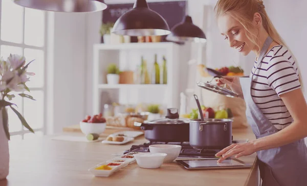 Mujer joven usando una tableta para cocinar en su cocina —  Fotos de Stock