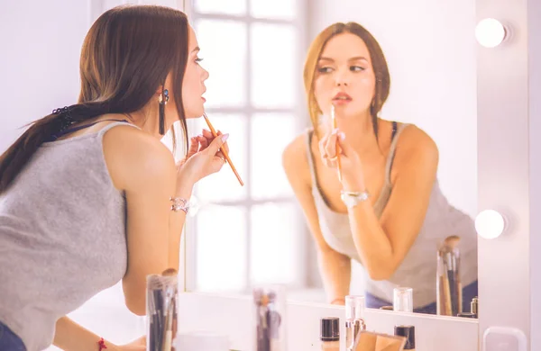 Junge Frau trägt Lippenstift vor dem Spiegel auf — Stockfoto