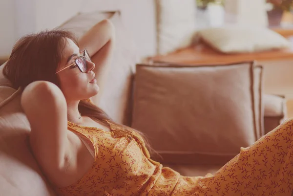 Uvolněná žena sedící doma na moderní pohovce — Stock fotografie