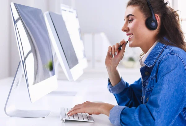 Mujer de negocios sonriente con auriculares usando portátil en el escritorio en el trabajo —  Fotos de Stock