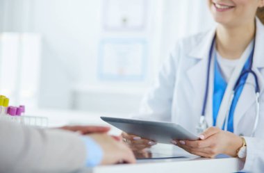 Kadın doktor hastane lobisinde tablet bilgisayar kullanarak, gülümseyerek