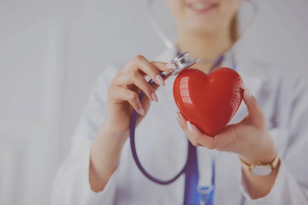 En läkare med stetoskop undersöka rött hjärta, isolerad på vit bakgrund — Stockfoto