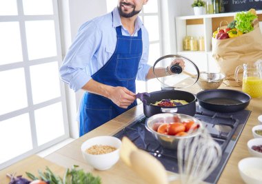 Adam ev mutfağında lezzetli ve sağlıklı yemekler hazırlıyor.