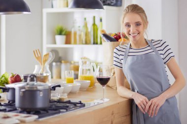 Güzel kadın mutfakta şarap içiyor.