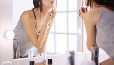 Genç kadın ruj bir ayna önünde uygulama