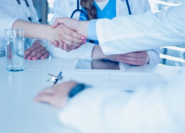 Doktor beyaz arka planda izole edilmiş bir hastayla el sıkışıyor.