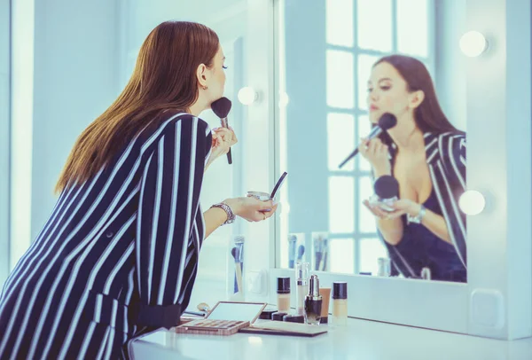 Belle fille regardant dans le miroir et appliquant cosmétique avec un gros pinceau — Photo