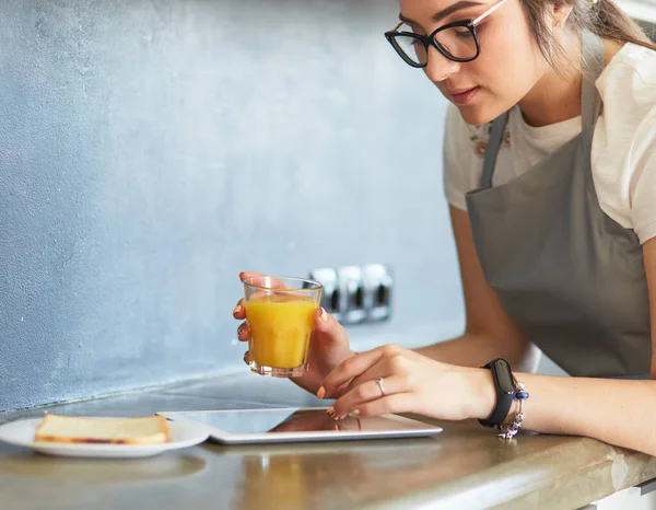 Çekici kadın mutfakta dikilirken elinde bir bardak portakal suyu tutuyor. — Stok fotoğraf
