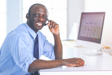 Kulaklıklı Afro-Amerikan işadamı laptopuyla çalışıyor.