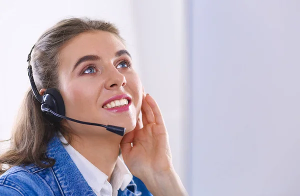 Heureuse charmante jeune femme assise et travaillant avec un ordinateur portable en utilisant un casque dans le bureau — Photo