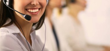 Ofisinde kulaklık ve bilgisayarla gülümseyen iş kadını ya da yardım hattı operatörü