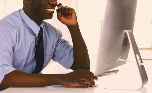 Afrikansk amerikansk affärsman på headset arbetar på sin bärbara dator — Stockfoto