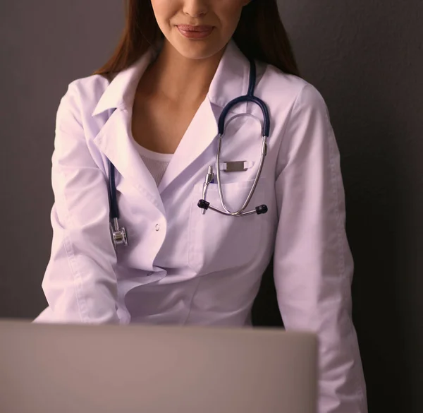 Médico femenino trabajando sentado sobre fondo gris — Foto de Stock