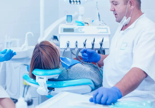 Médico dentista sênior em consultório odontológico conversando com paciente do sexo feminino e se preparando para o tratamento — Fotografia de Stock