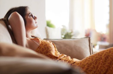 Evdeki modern bir kanepede oturan rahat kadın.