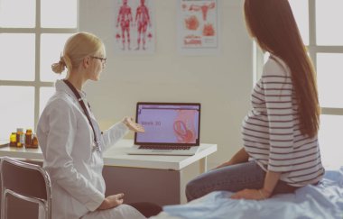 Hastanede doktorla gülümseyen güzel bir hamile kadın.