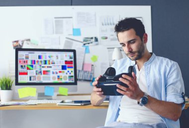 Genç erkek yazılım programcısı ofiste üç boyutlu sanal gerçeklik gözlükleriyle yeni bir uygulama test ediyor..