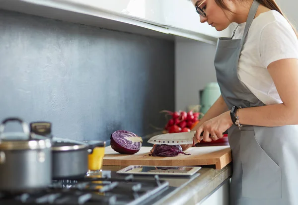 Yeni mutfakta yemek pişiren kadın sebzelerle sağlıklı yemekler yapıyor. — Stok fotoğraf