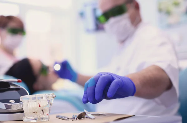 El dentista masculino mayor ajusta el reflector antes de comenzar a trabajar — Foto de Stock