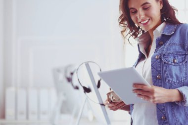 Gülümseyen kadın kahve içiyor ve kafede tablet kullanıyor.