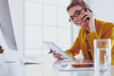 Güzel bir kadının portresi, iş yerinde dizüstü bilgisayarının önünde otururken ve yeni bir proje üzerinde çalışırken arama yapıyor.