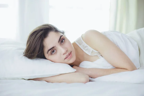 Pretty woman lying down on her bed at home — Stock Photo, Image