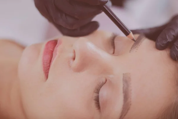 Cosmetologist applying permanent make up on eyebrows — Stock Photo, Image