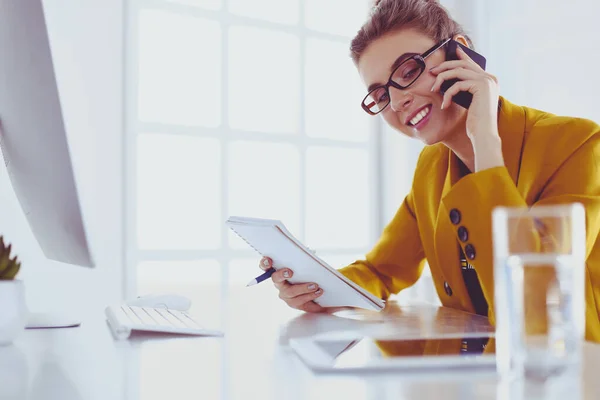 Ritratto di bella donna che chiama mentre siede sul posto di lavoro davanti al computer portatile e lavora a un nuovo progetto — Foto Stock