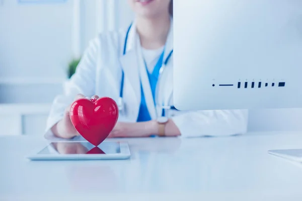 Medico femminile con stetoscopio che tiene il cuore, su sfondo chiaro — Foto Stock