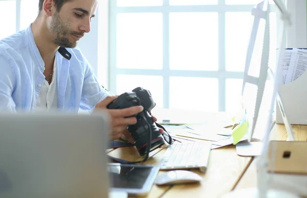 Retrato del joven diseñador sentado en el estudio gráfico frente a la computadora portátil y el ordenador mientras trabaja en línea. — Foto de Stock