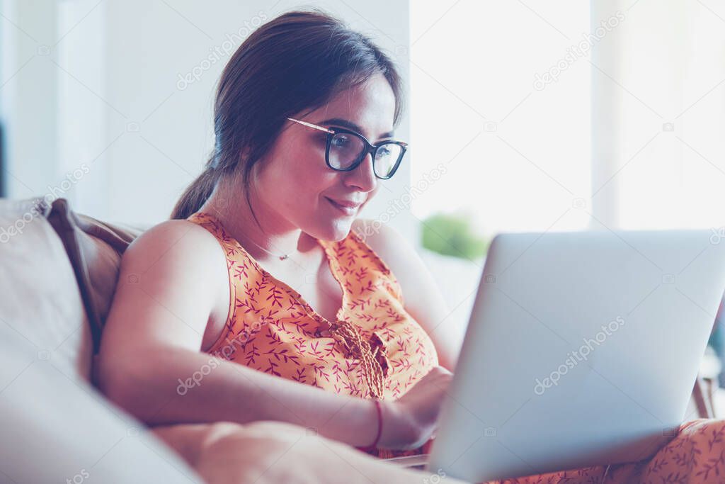 Young woman sitting on couch working on laptop computer at home