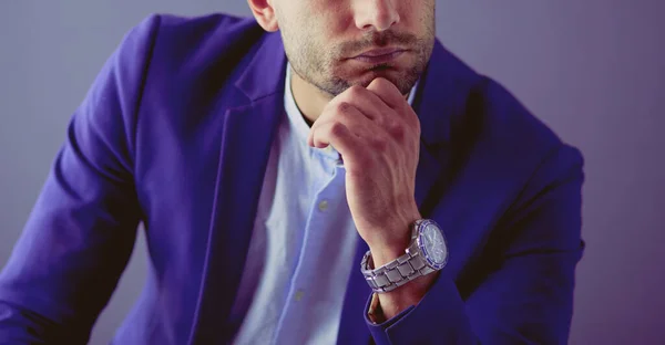 Joven empresario sentado aislado sobre fondo gris. —  Fotos de Stock