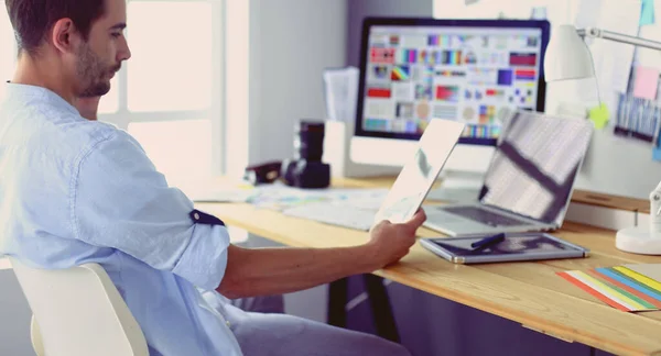 Porträt eines jungen Designers, der im Grafikstudio vor Laptop und Computer sitzt, während er online arbeitet. — Stockfoto